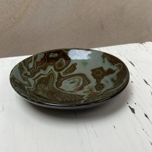 Ceramic plate with brown and green glaze on a white surface