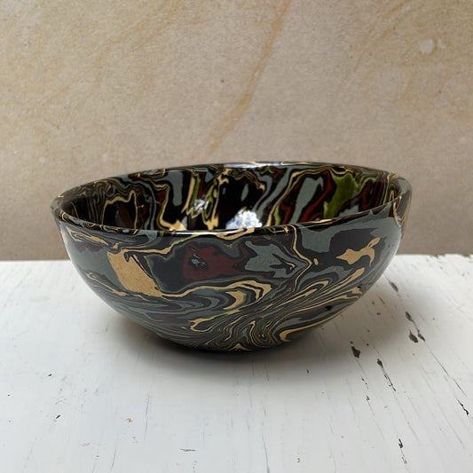 Black marbled ceramic bowl on a white surface with a beige background