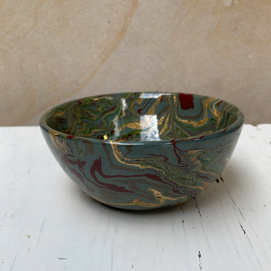 Decorative ceramic bowl with marbled design on a white surface.