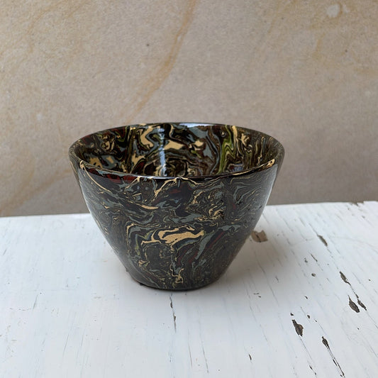 Black ceramic bowl on a white surface with a beige background