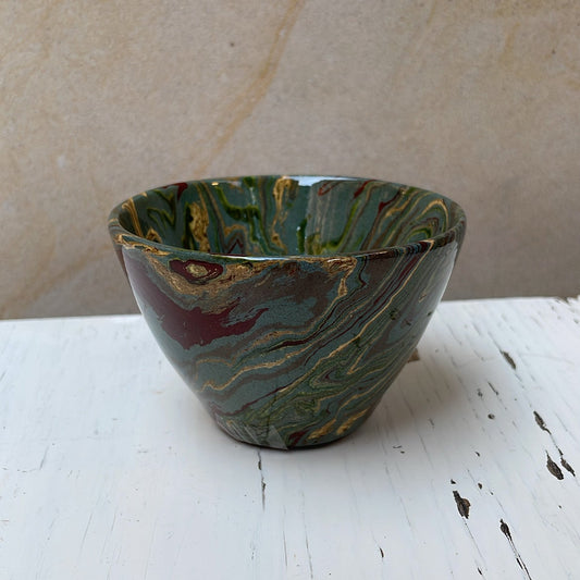 Handmade ceramic bowl with a swirling pattern on a white surface.