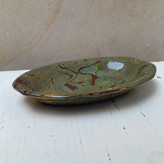 Green ceramic dish on a white surface with a beige background