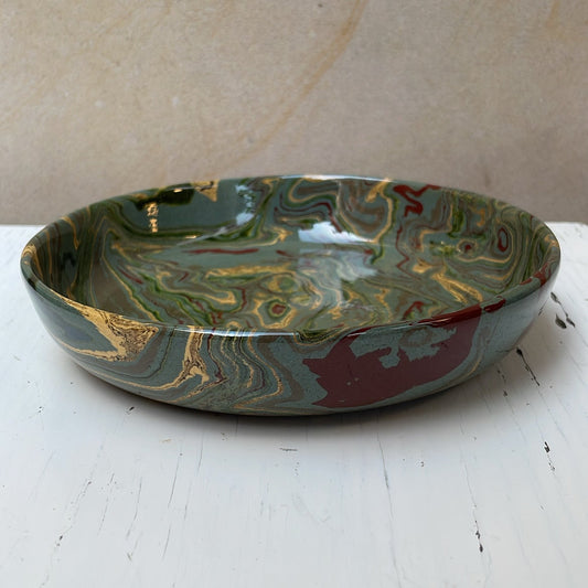 Marbled ceramic bowl on a white surface with a beige background