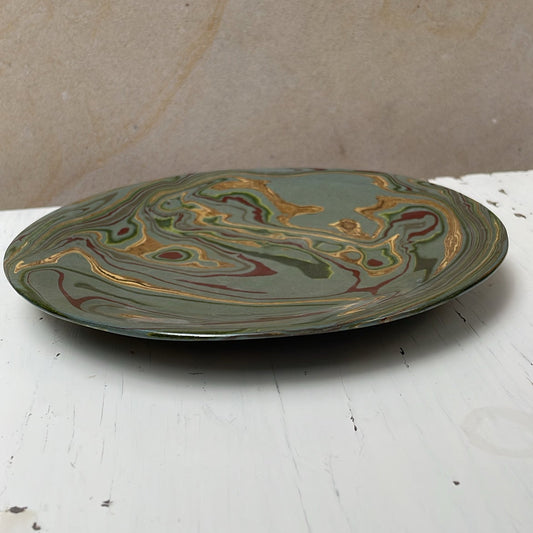 Decorative ceramic plate with marbled design on a white surface