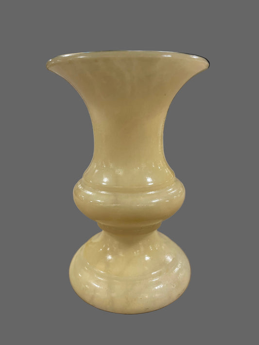 Beige ceramic vase on a textured surface with a blurred background