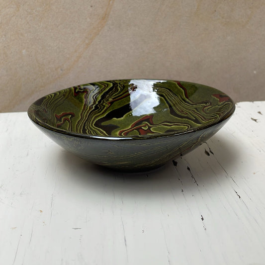Green ceramic bowl on a white surface with a beige background