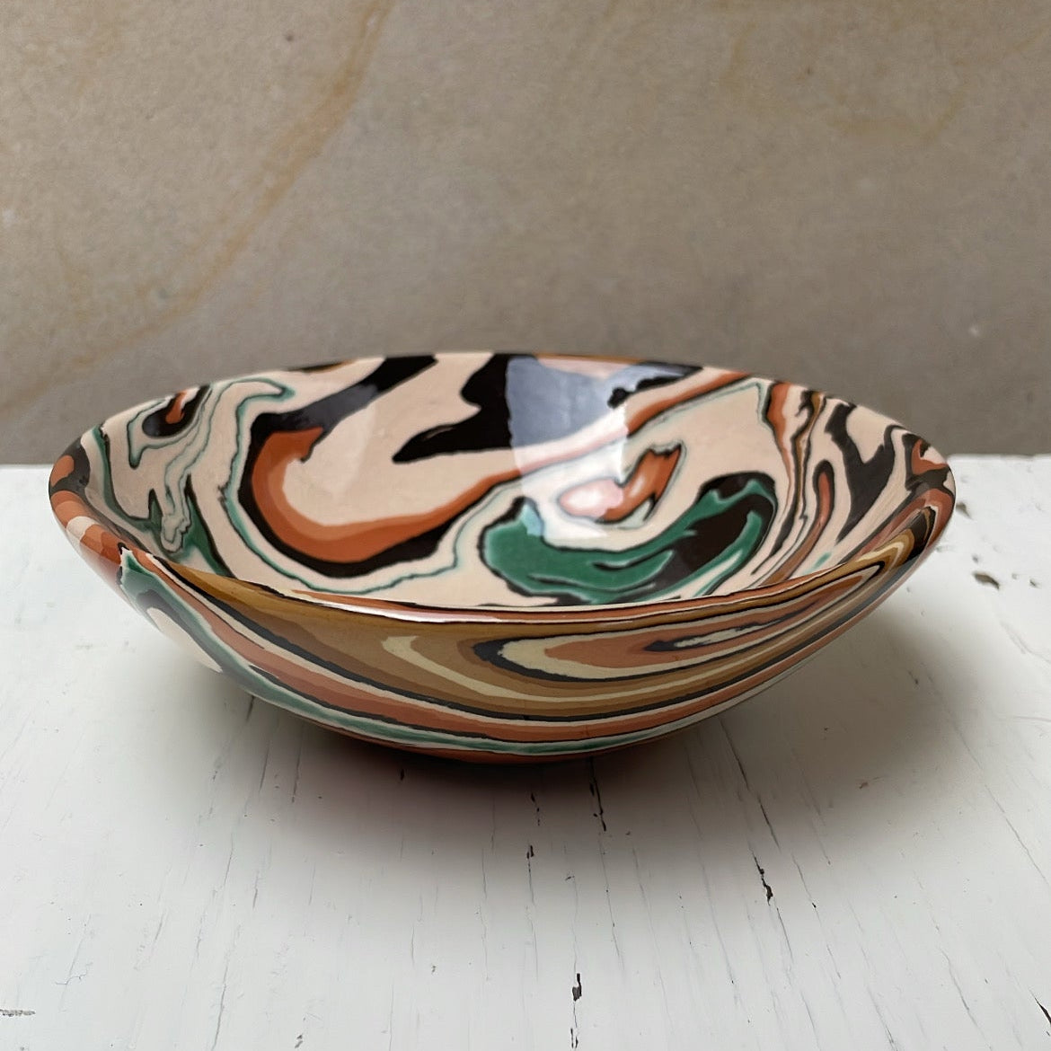 Marbled ceramic bowl on a white surface with a beige background