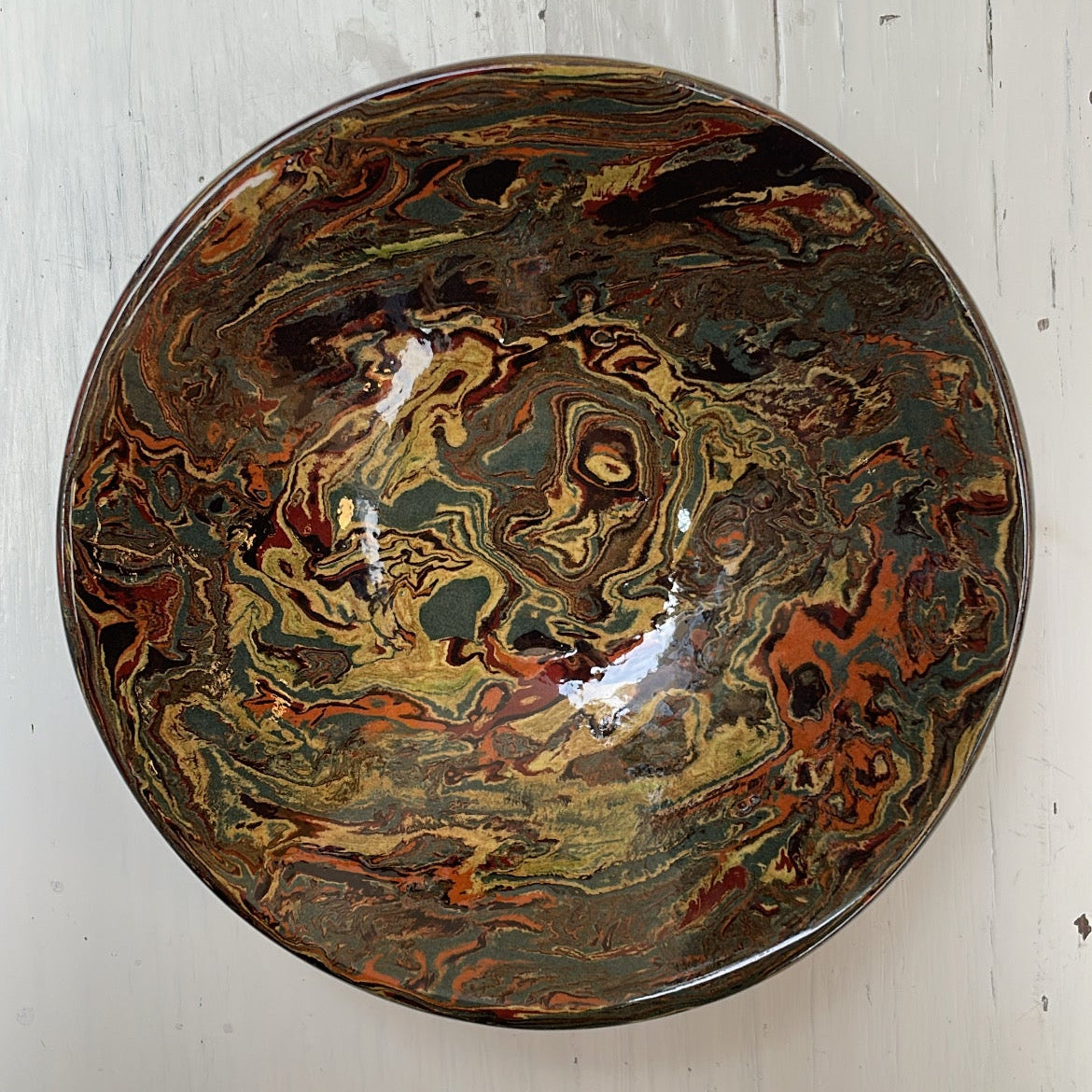 Decorative ceramic bowl with marbled design on a white wooden surface