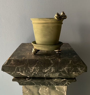 Green pot on a decorative marble pedestal against a plain background
