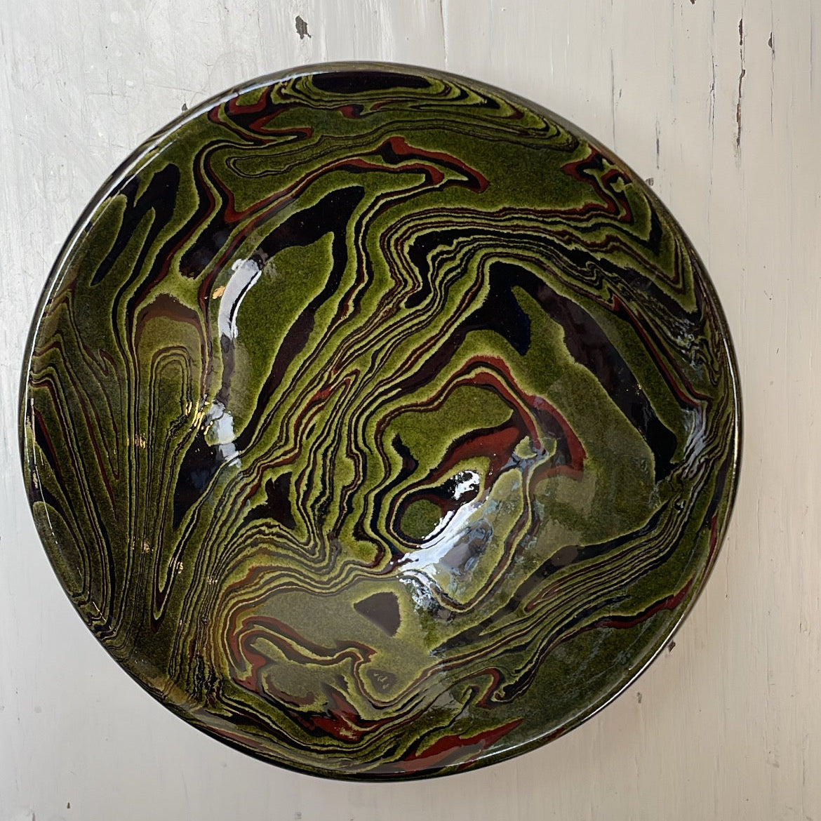 Decorative bowl with marbled pattern on a white wooden surface