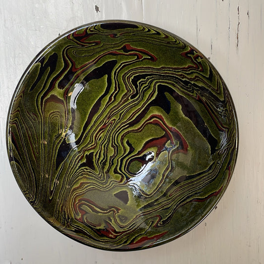 Decorative bowl with marbled pattern on a white wooden surface