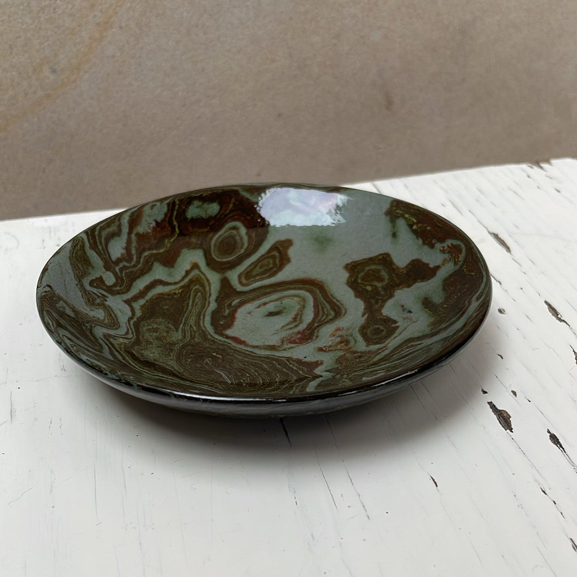 Ceramic plate with brown and green glaze on a white surface