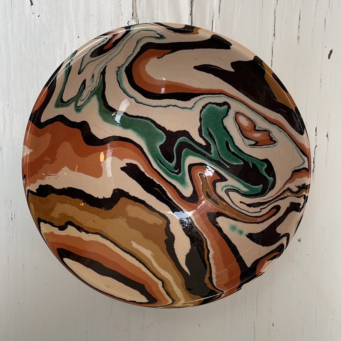 Round ceramic bowl with marbled design on a white wooden surface