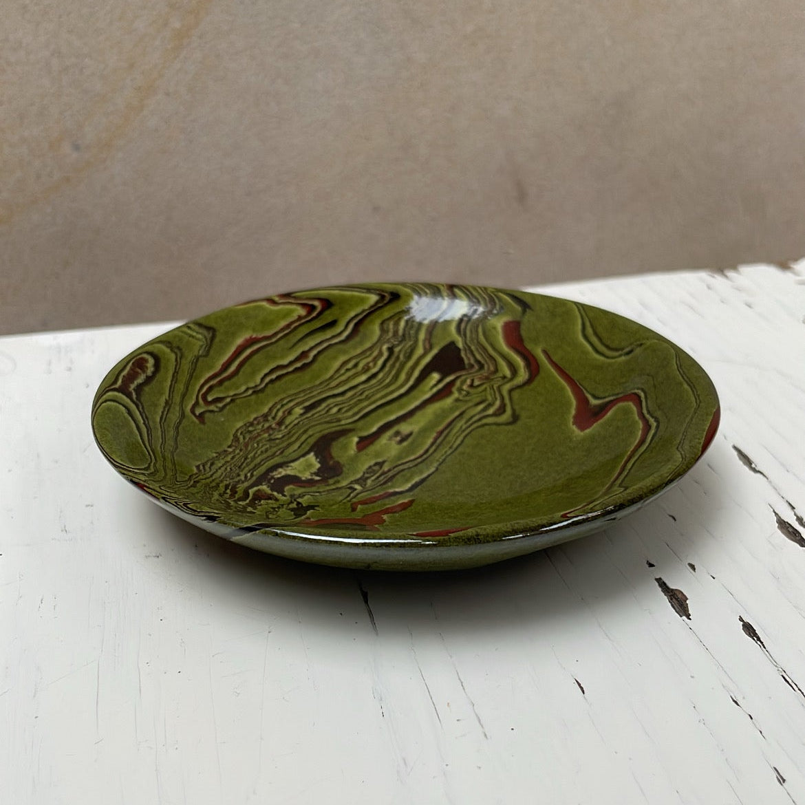 Green ceramic plate with marbled design on a white surface