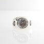 A sterling silver cocktail ring with a clear Rock Crystal centerpiece and two white topaz stones set in a bezel frame.