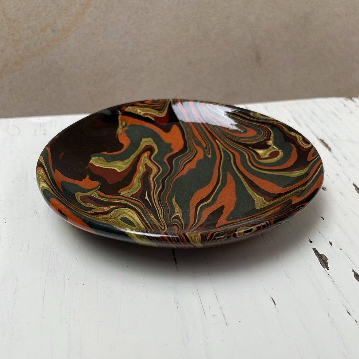 Marbled ceramic plate on a white surface with a beige background