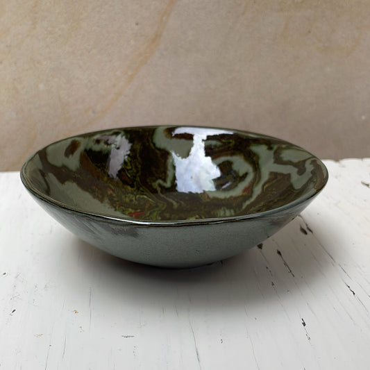 Green ceramic bowl on a white surface with a beige background