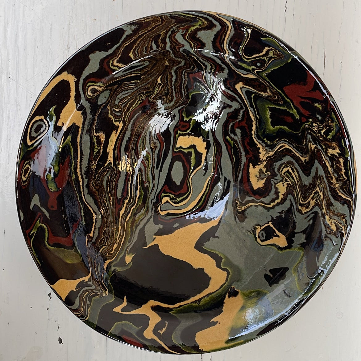 Decorative plate with marbled design on a white wooden surface