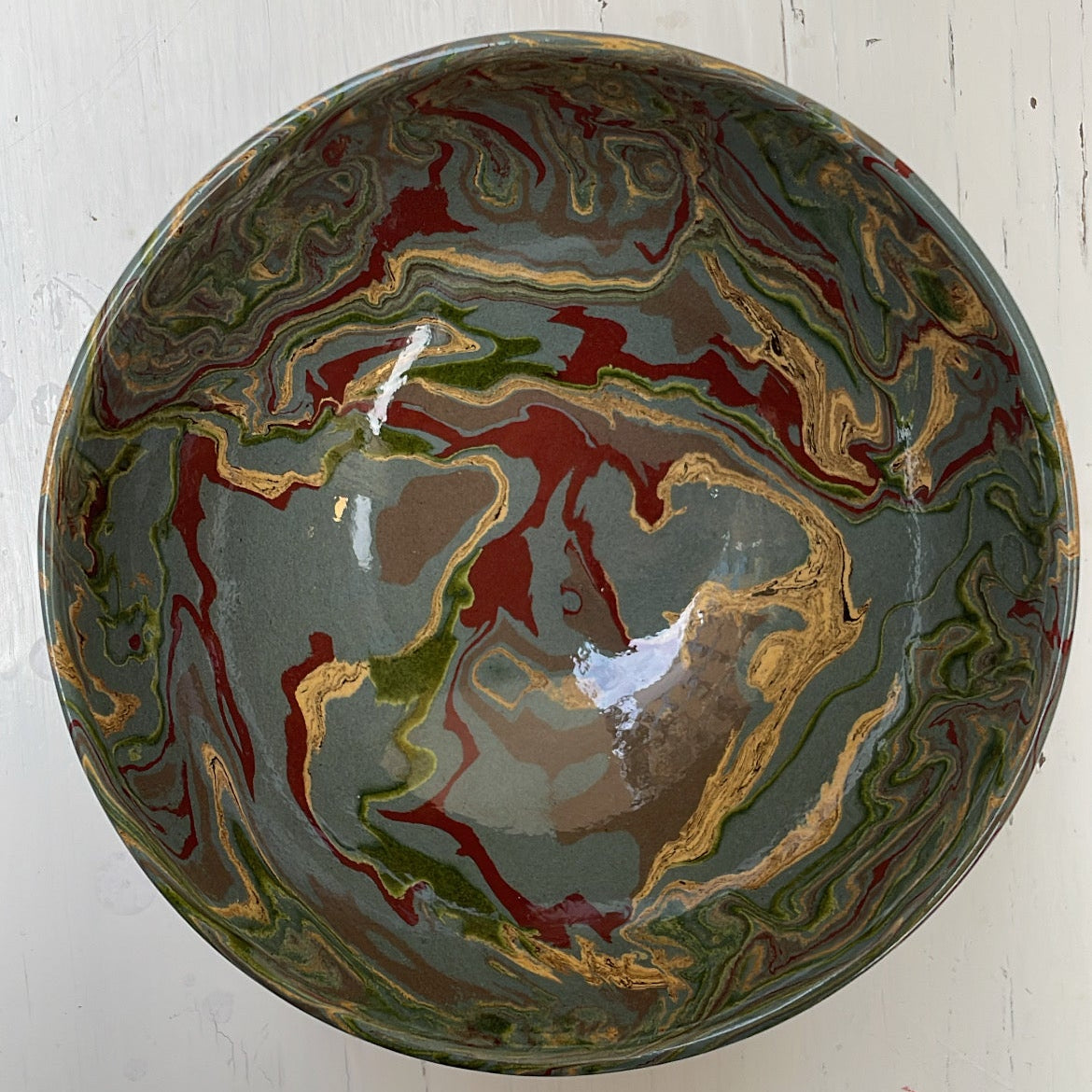 Decorative ceramic bowl with marbled design on a white wooden surface