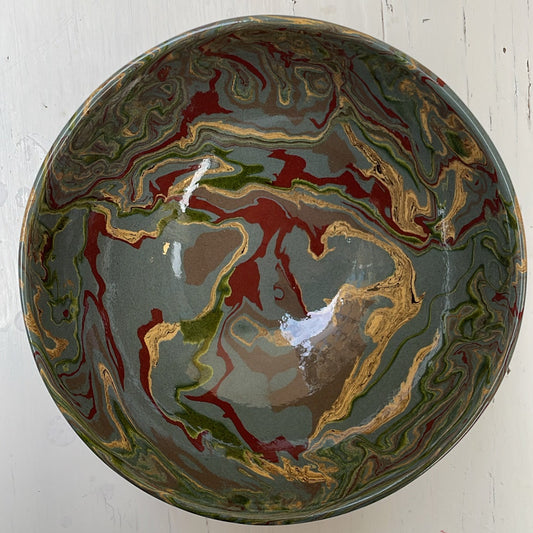 Decorative ceramic bowl with marbled design on a white wooden surface
