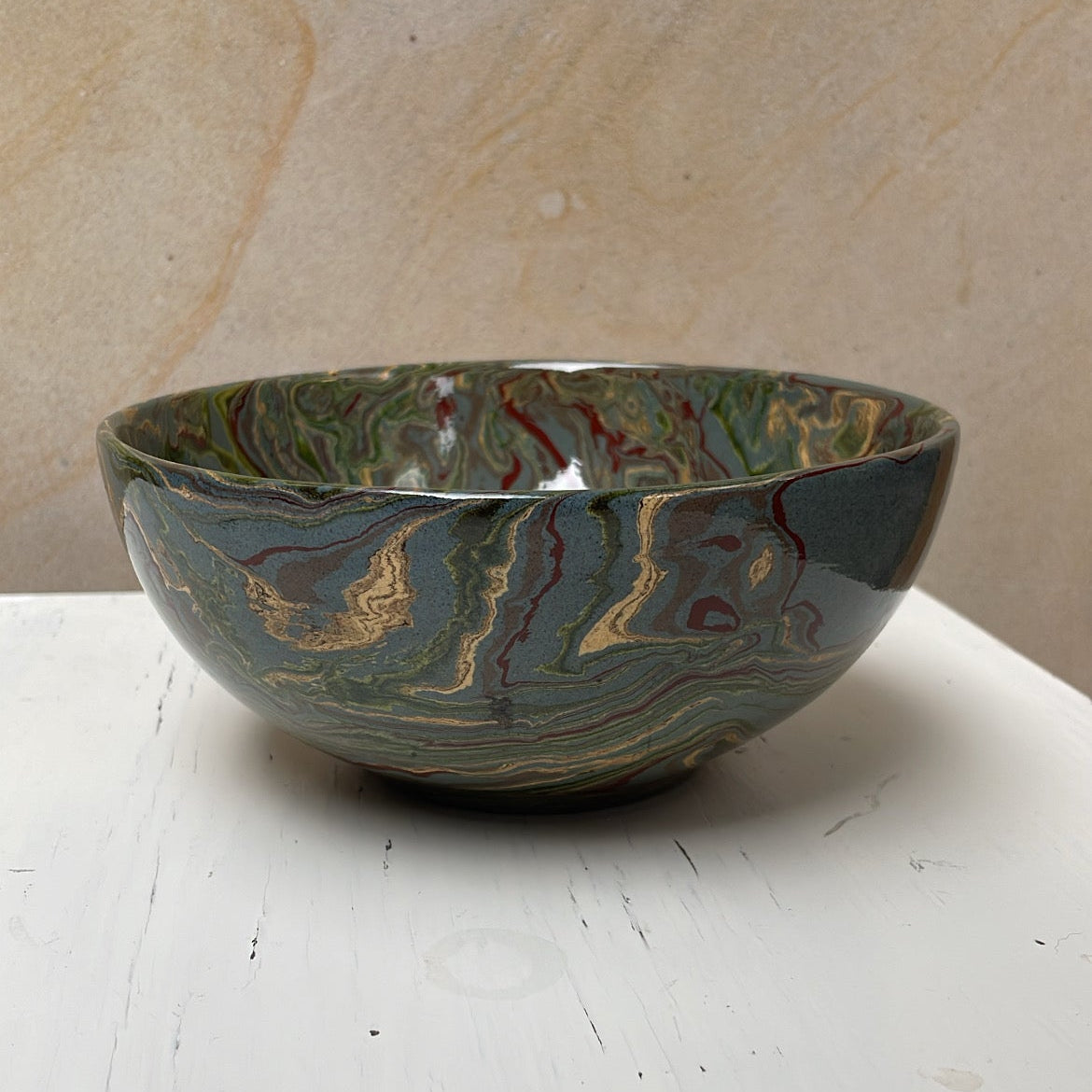 Marbled ceramic bowl on a white surface with a beige background