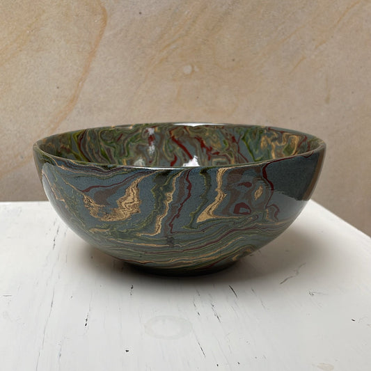 Marbled ceramic bowl on a white surface with a beige background