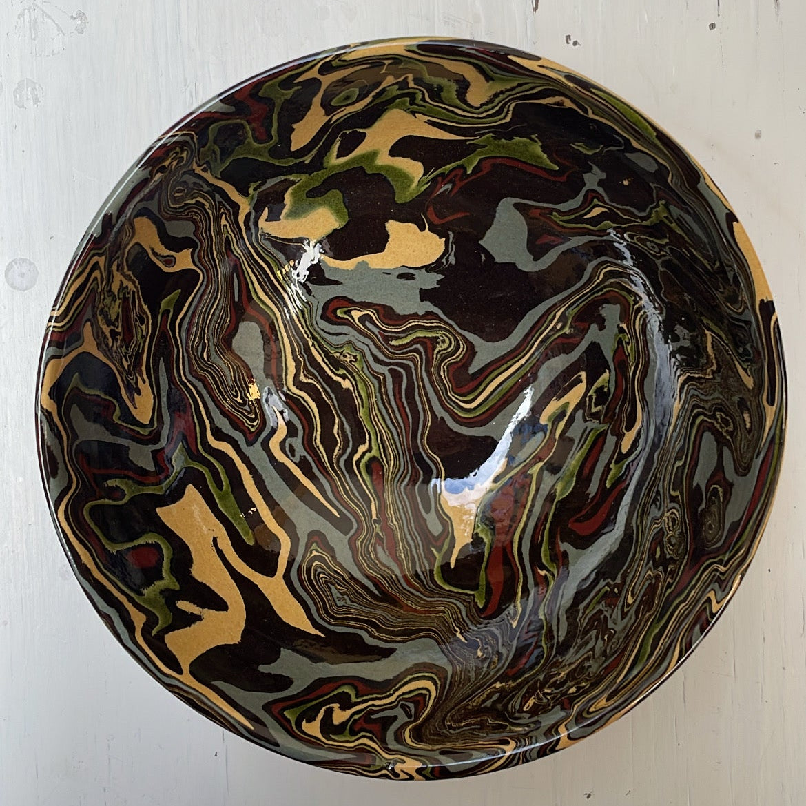 Round ceramic bowl with marbled design on a white wooden surface