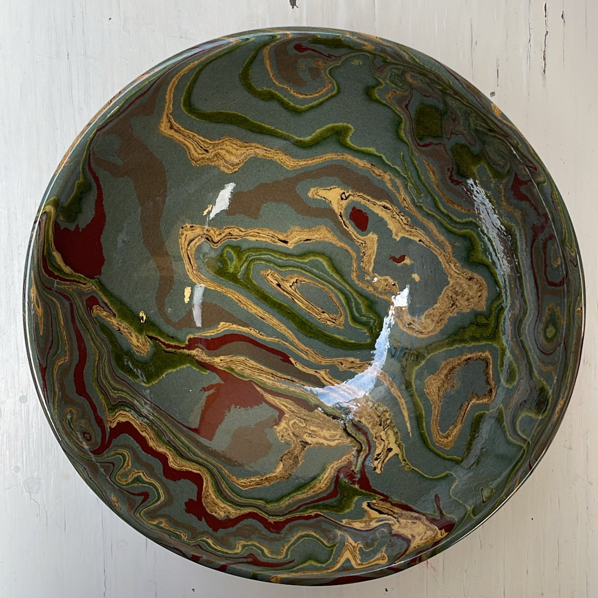 Decorative ceramic bowl with marbled design on a white wooden surface