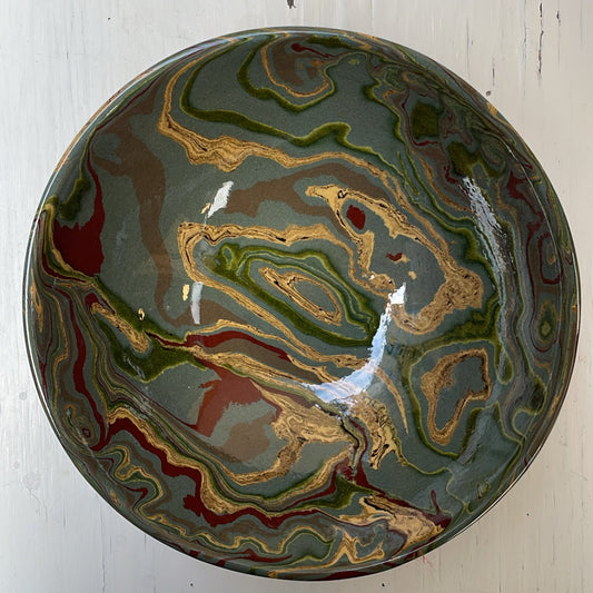 Decorative ceramic bowl with marbled design on a white wooden surface