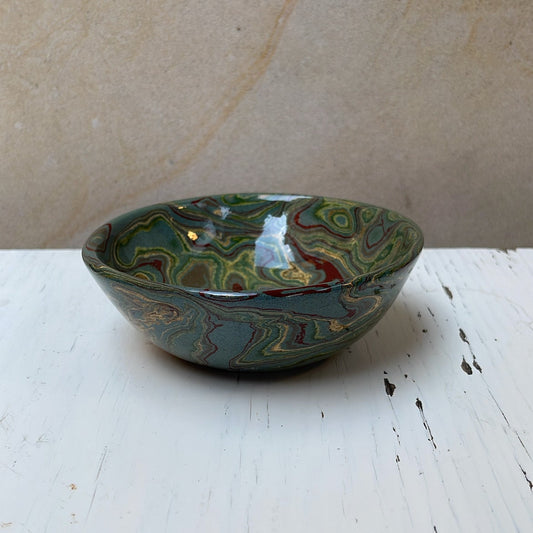 Decorative ceramic bowl with marbled design on a wooden surface