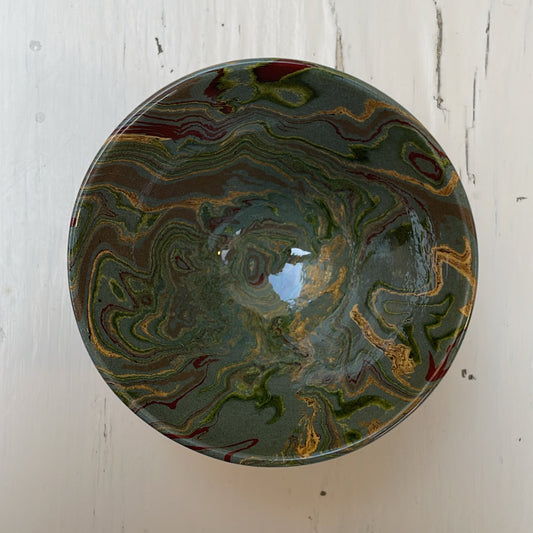 Decorative ceramic bowl with marbled design on a white wooden surface