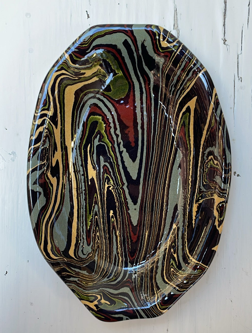 Decorative plate with marbled pattern on a white wooden surface