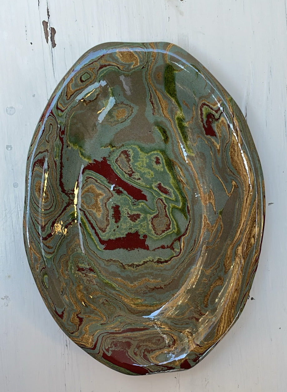 Decorative ceramic plate with swirling green and gold patterns on a white background