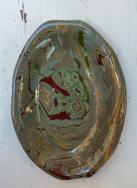 Decorative ceramic plate with swirling green and gold patterns on a white background