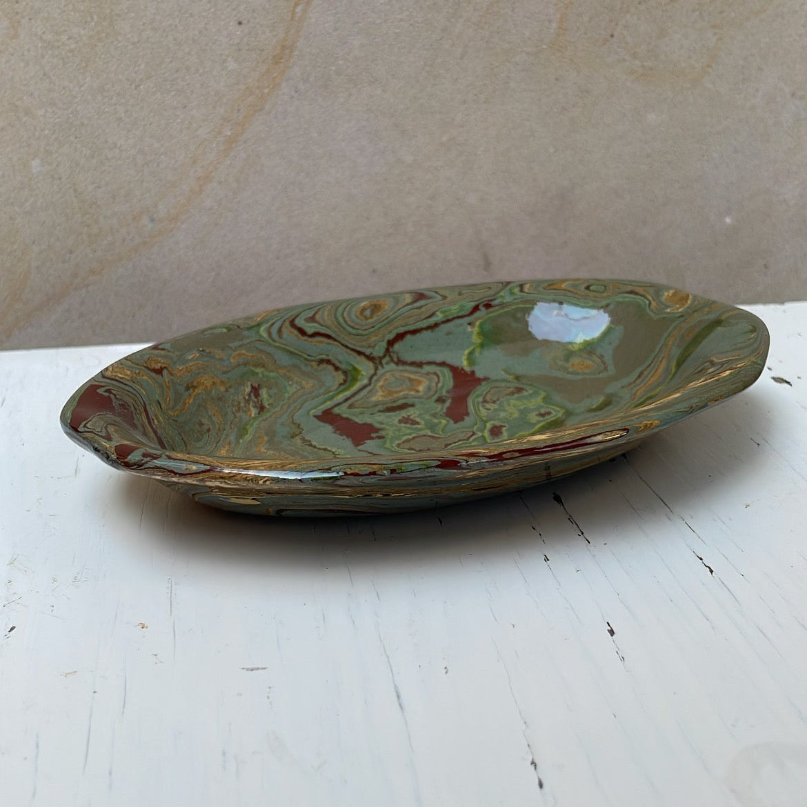 Green ceramic dish on a white surface with a beige background