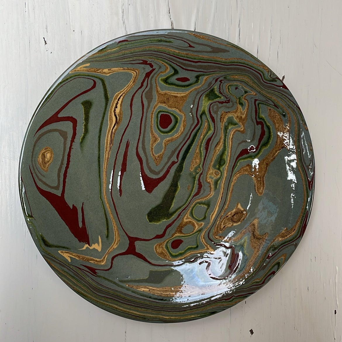 Round ceramic plate with marbled design on a white wooden surface