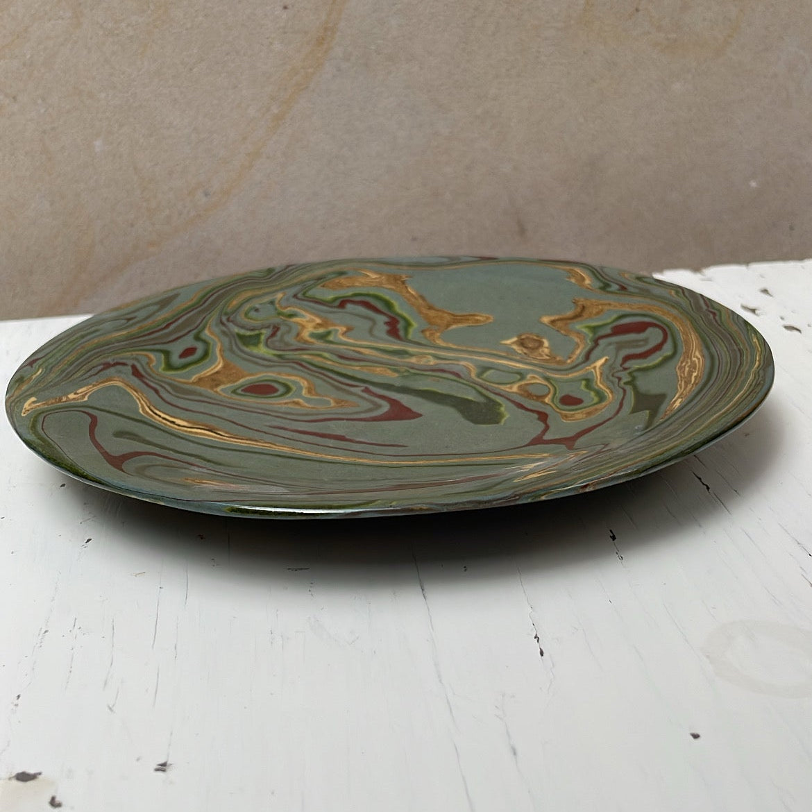 Decorative ceramic plate with marbled design on a white surface