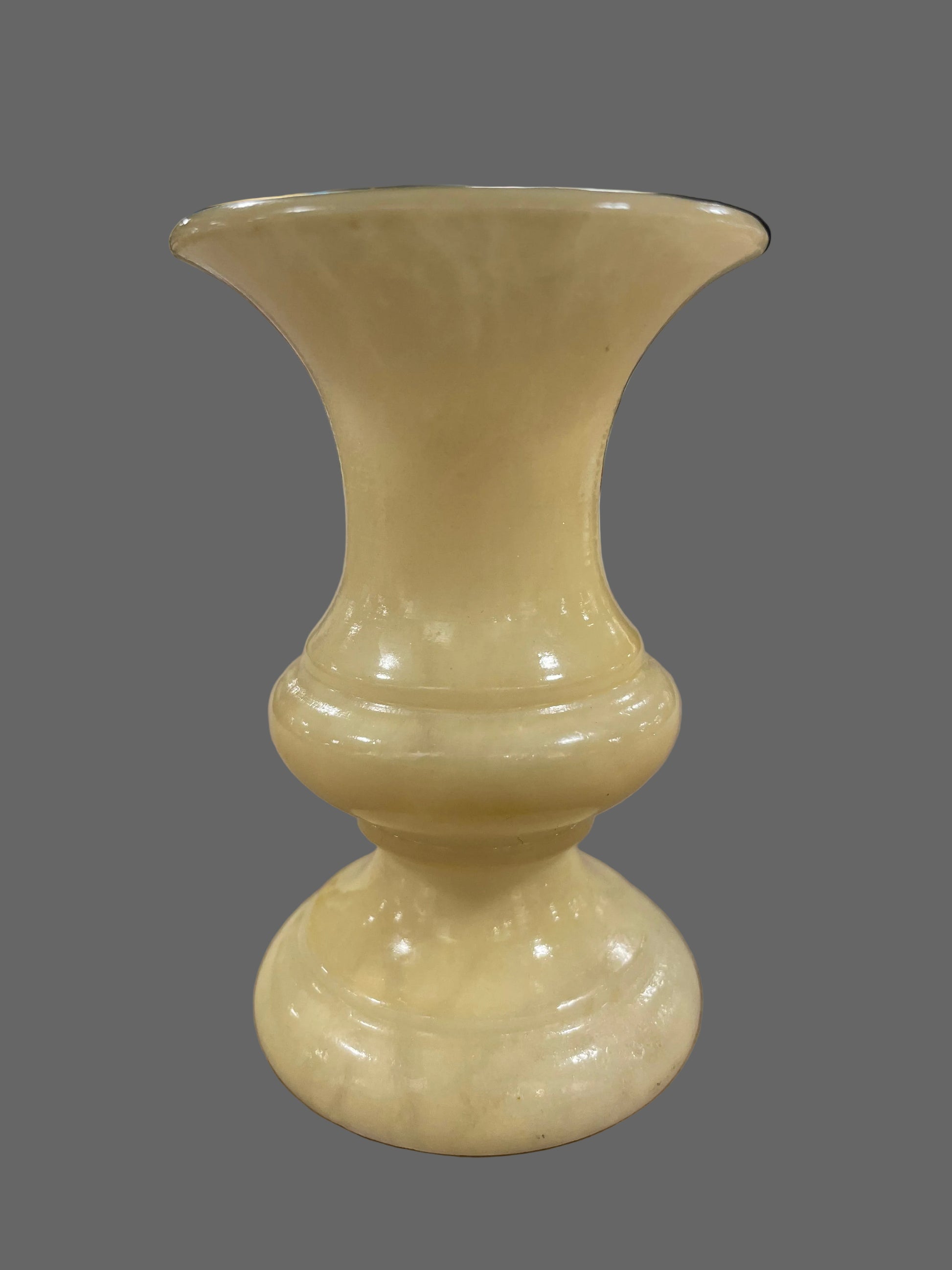 Beige ceramic vase on a textured surface with a blurred background