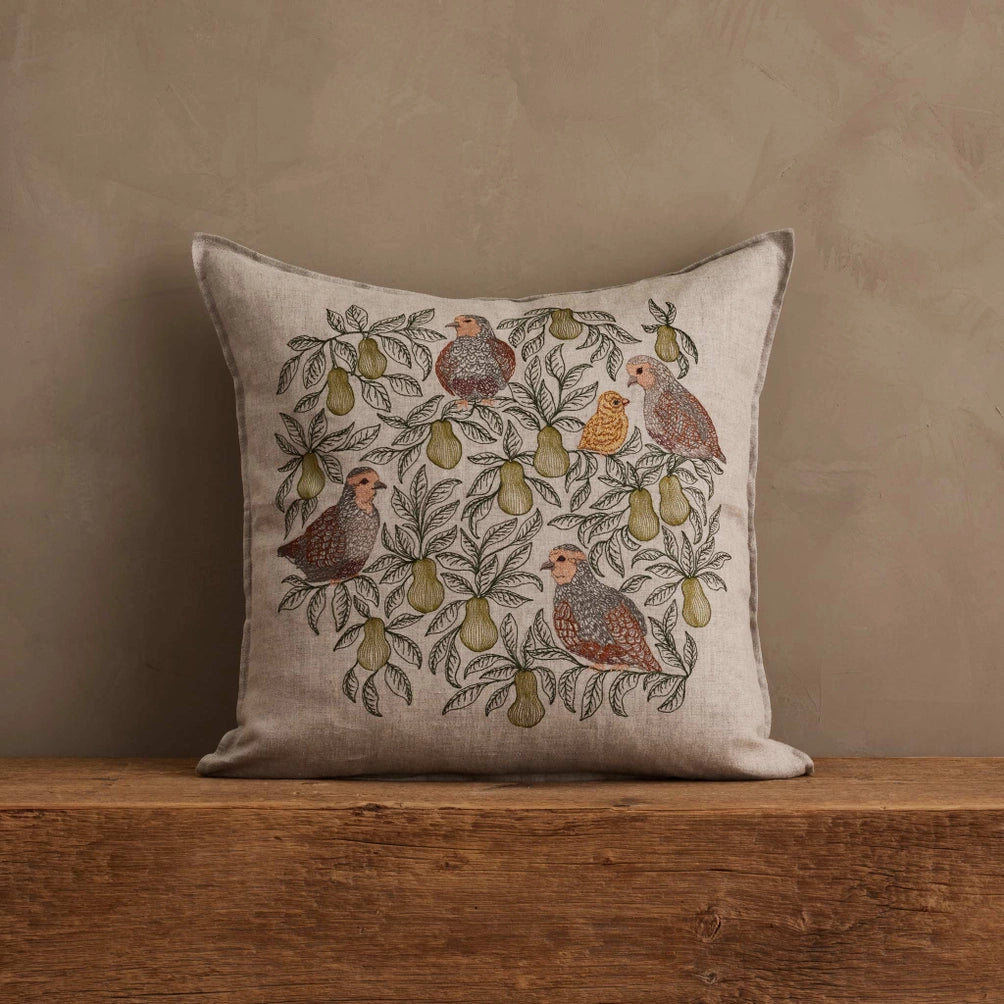 Coral & Tusk Partridge in a Pear Tree pillow styled on a wooden surface