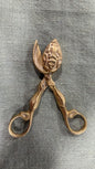 Vintage brass wick trimmer, 14 cm long, with sculptural handles, round finger loops and decorative relief on its curved wick-catching head
